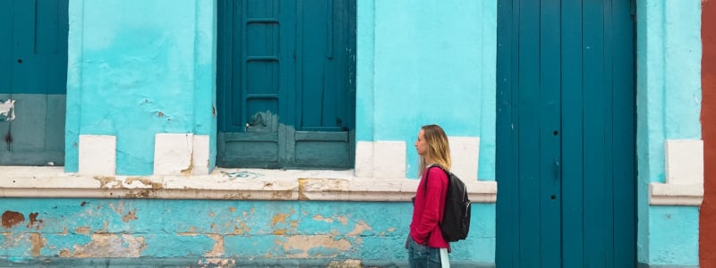 A woman walking past a blue building.