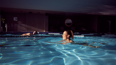 A man and a woman swimming in an indoor pool.