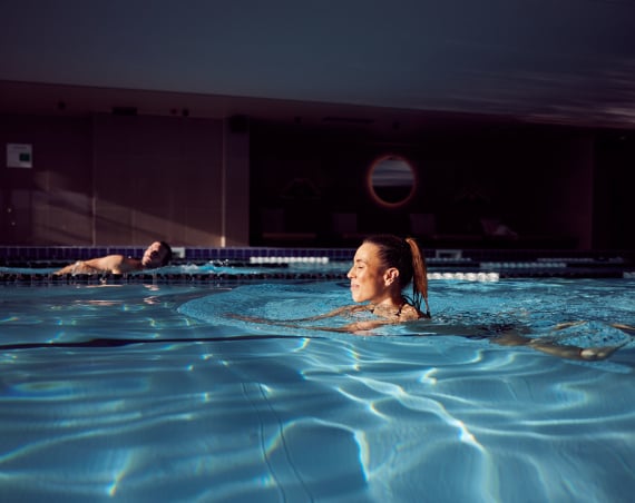 A man and a woman swimming in an indoor pool.