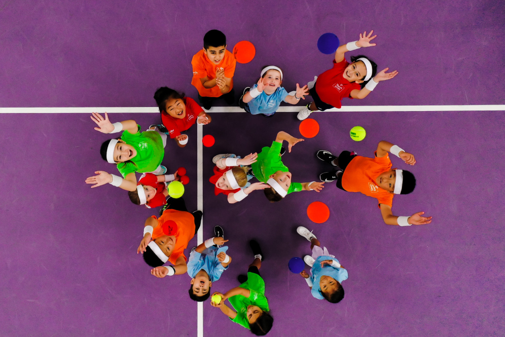 alt="Bambini che partecipano ad attività sportive indoor su un campo multisport durante un allenamento di gruppo"