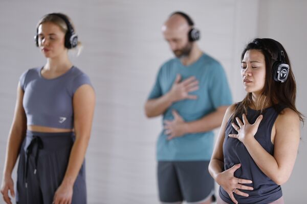 Partecipanti alla lezione SPIRIT Dance Meditation con cuffie durante esercizi di respirazione e meditazione.
